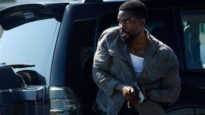 A character from Man on Fire is sitting on the couch, looking forward. 